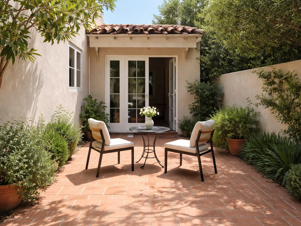 Enclosed paved patio courtyard outside a home, connected to the house with privacy walls and simple outdoor seating