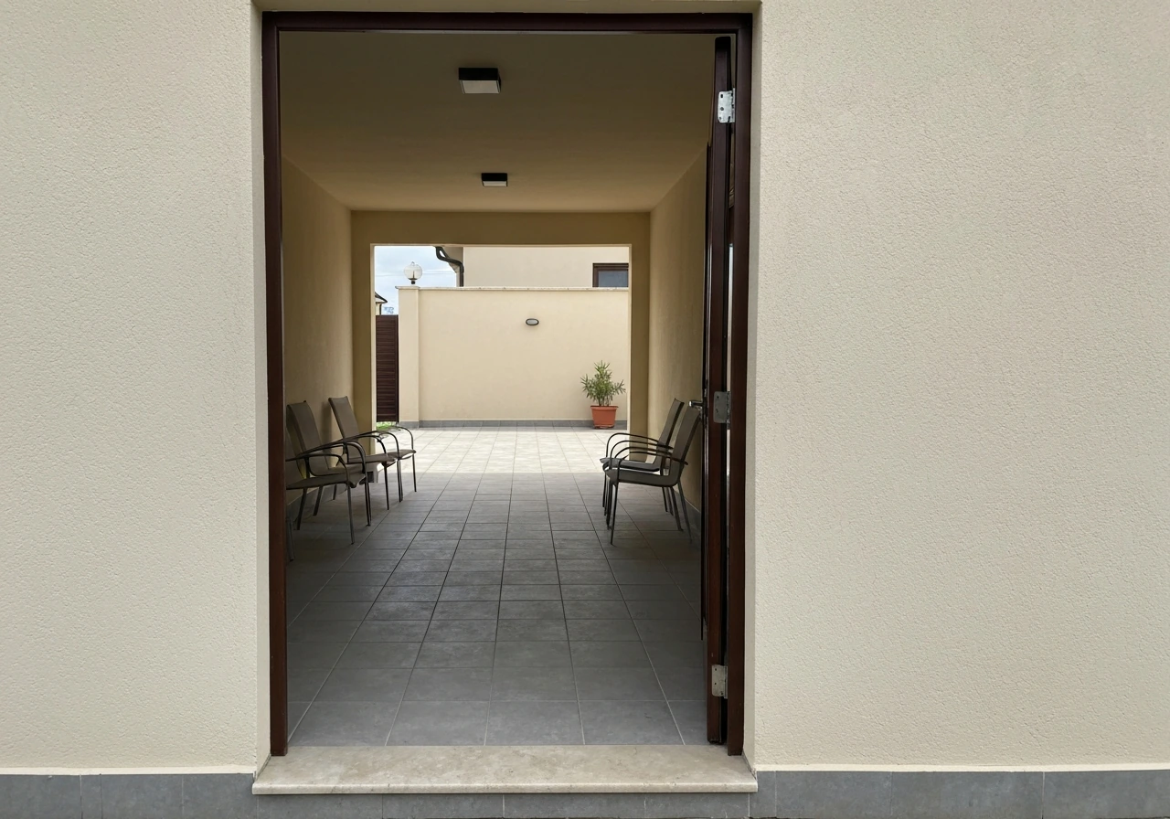 Open roofless paved patio directly connected to a house, with simple outdoor seating and no people.