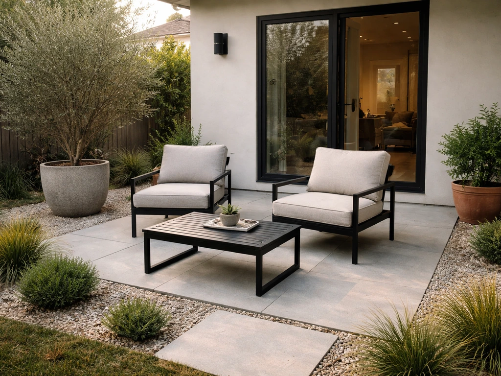 Ground-level residential patio with outdoor seating and paved surface beside a home.